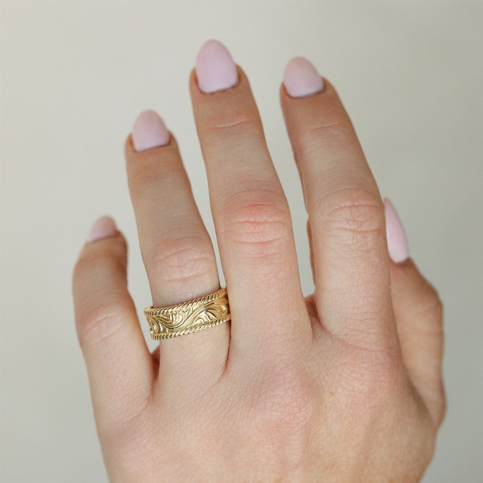 An engraved yellow gold band on a hand